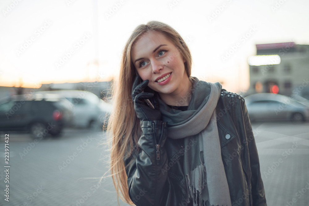Young girl is ringing on the street in the jacket