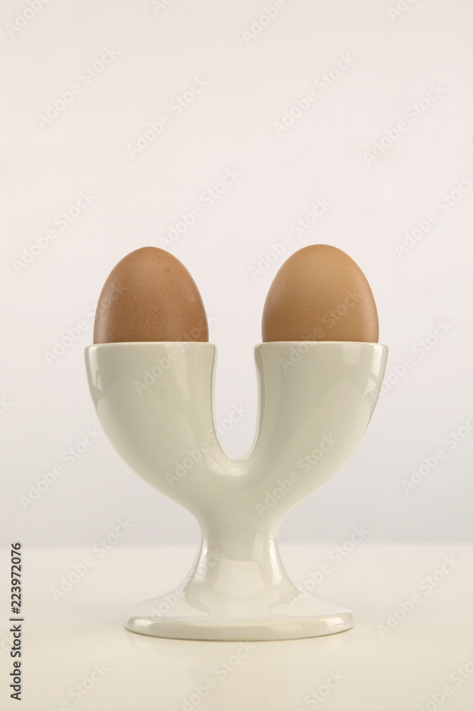 TWO BROWN EGGS IN DOUBLE WHITE EGG CUP TWO BROWN EGGS IN DOUBLE WHITE EGG CUP