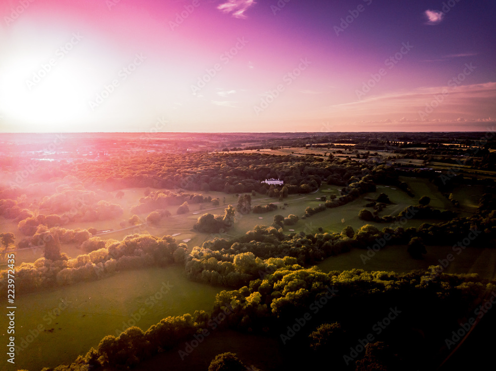 Aerial view of the countryside around London taken at sun set. Dramatic lighting cast on threes and hedgerows as the sun sets, taken from the air