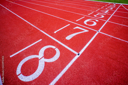 red surface running racetrack with white lines and number in outdoor stadium © antpkr