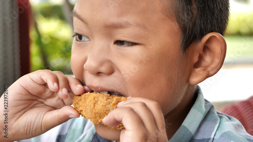 Cute asian boy are happy eating fried chicken leg in restaurant