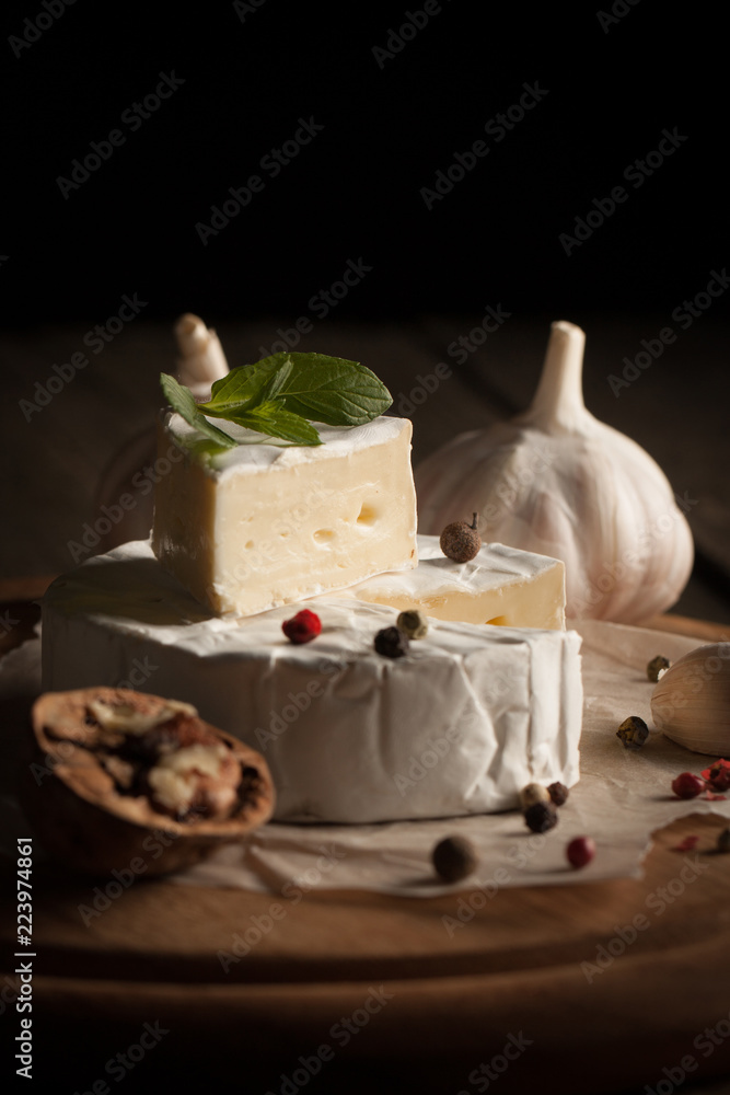 Camembert and brie cheese on wooden background with tomatoes, letuce and garlic. Italian food. Dairy products.