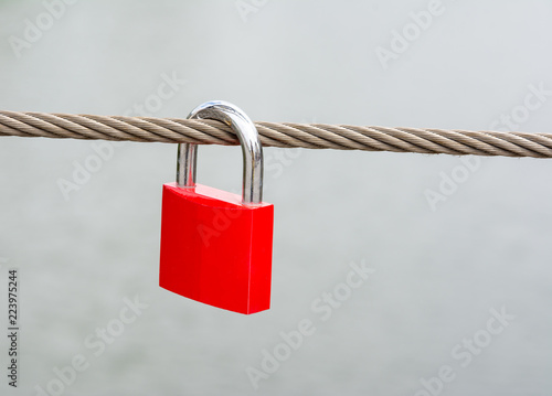 Red padlock hanging on a steel cable