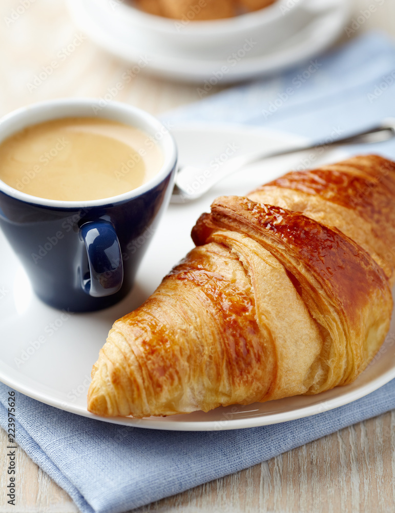 Croissant and a cup of coffee on a plate. Concept for a tasty breakfast. Close up. 
