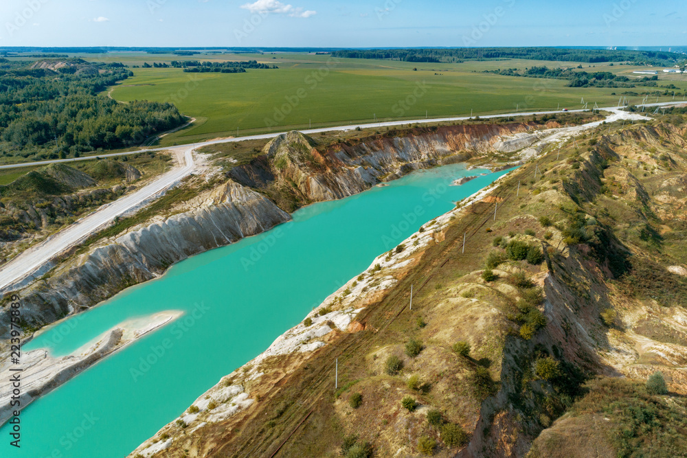 Fototapeta premium Abandoned mountain quarry. The mine workings are filled with water of a deep blue color. Aerial view