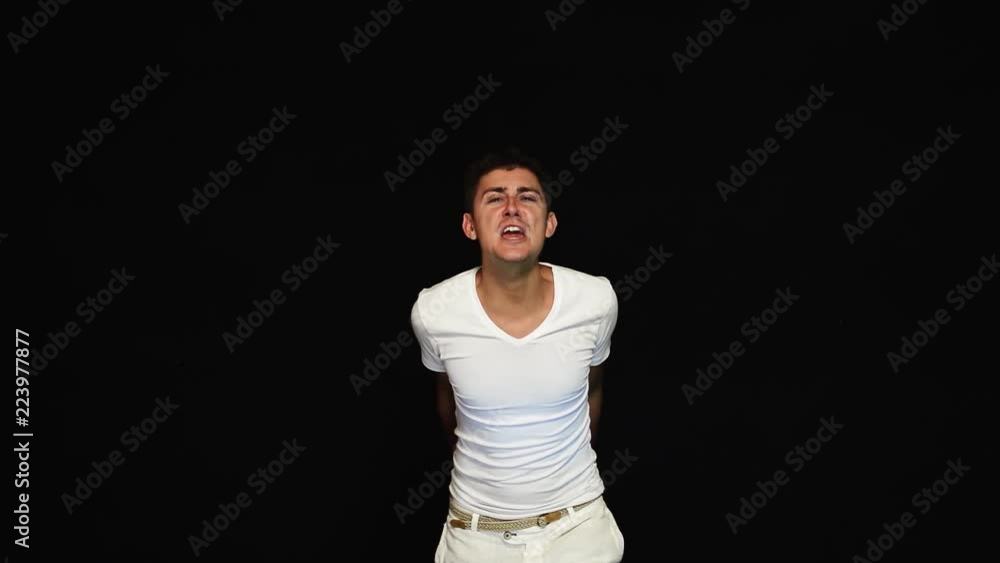 Energetic nice looking charismatic guy with big blue eyes and stylish haircut dressed in white clothes is emotionally singing and looking at of camera in studio on black background. Energetic nice looking charismatic guy with big blue eyes and stylish haircut dressed in white clothes is emotionally singing and looking at of camera in studio on black background.