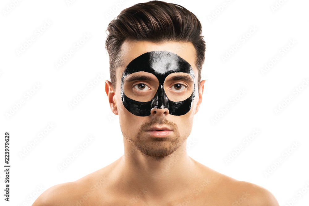Young guy with a black charcoal mask on his face on white background. Young guy with a black charcoal mask on his face on white background.