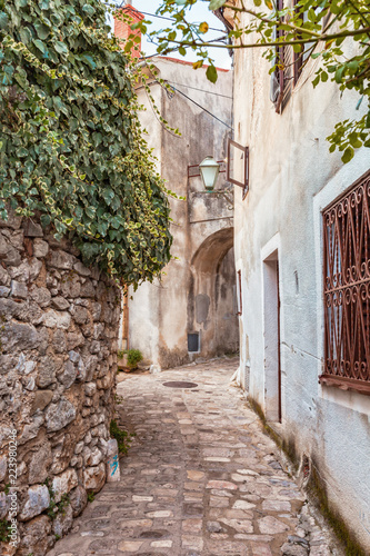 Narrow street with old stone houses in Krk Croatia