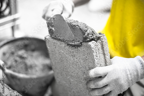 Close up of industrial bricklayer installing bricks on construction site, building walls.