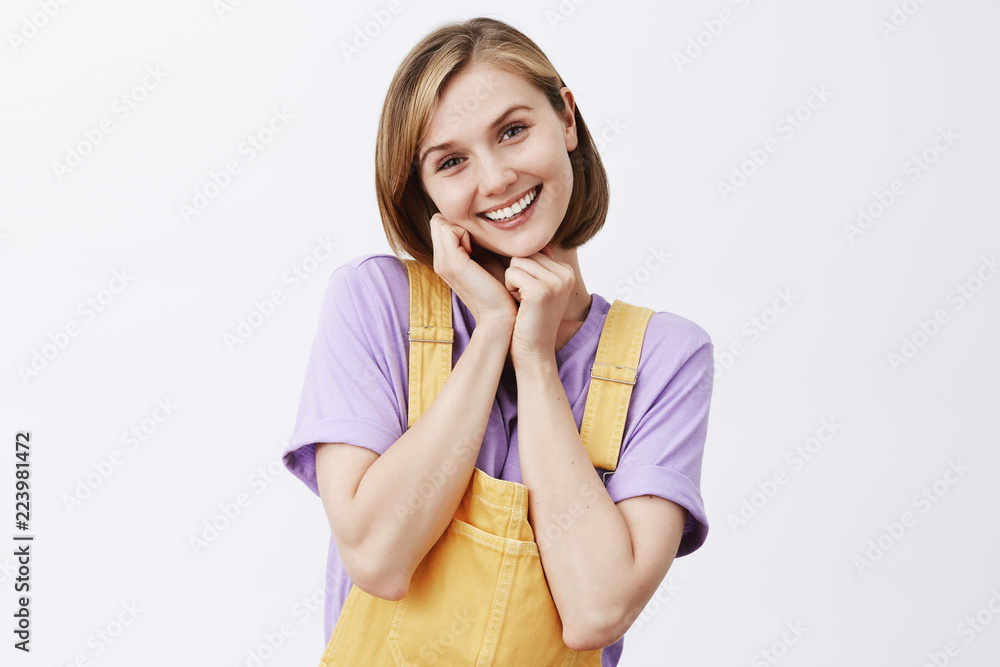 Oh you are so sweet. Charmed and pleased tender girlfriend with blond short haircut wearing yellow dungarees, tilting head and holding hands near face, being touched and gazing with admiration Oh you are so sweet. Charmed and pleased tender girlfriend with blond short haircut wearing yellow dungarees, tilting head and holding hands near face, being touched and gazing with admiration