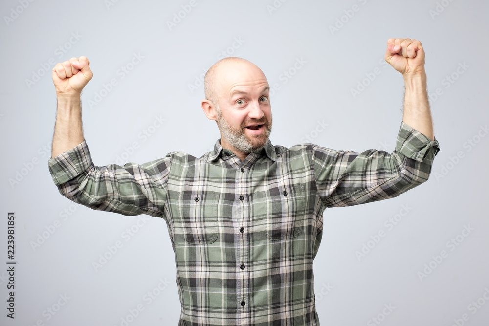 Positive emotional man smiles, shows muscles on his arms, feels proud to be strong. Positive emotional man smiles, shows muscles on his arms, feels proud to be strong.