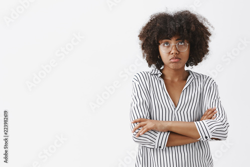 What a bummer. Gloomy and upset good-looking African American woman feeling gloomy and regretting plans for night ruined pursing lips looking up and crossing hands on chest from disappointment
