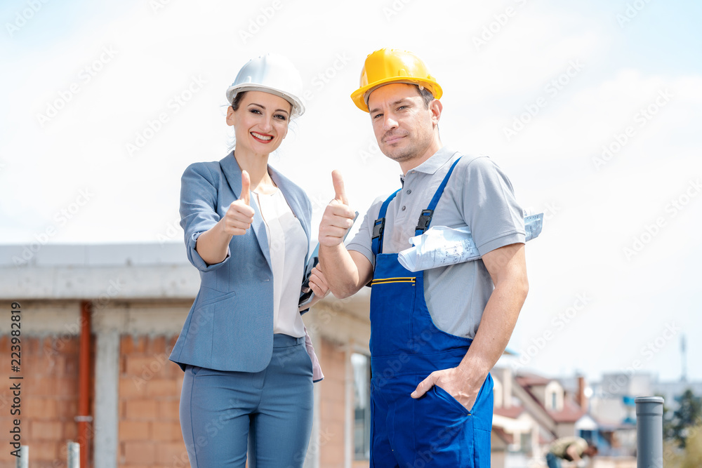 Architect and Construction worker on site giving thumbs-up to the camera Architect and Construction worker on site giving thumbs-up to the camera