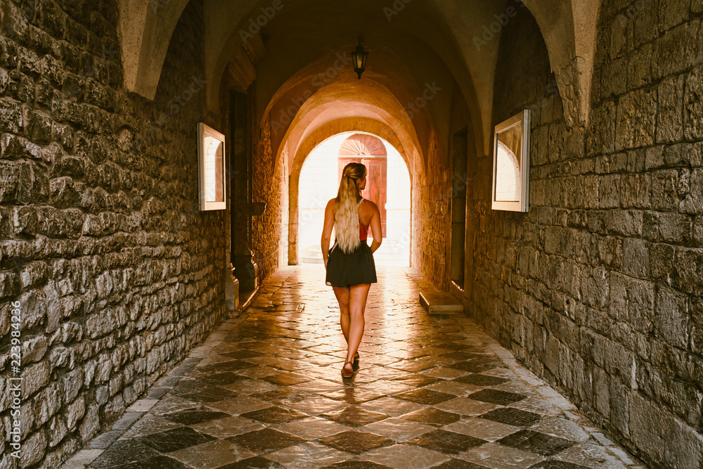 Tourist woman walking across medieval stone tunnel, Krk Croatia