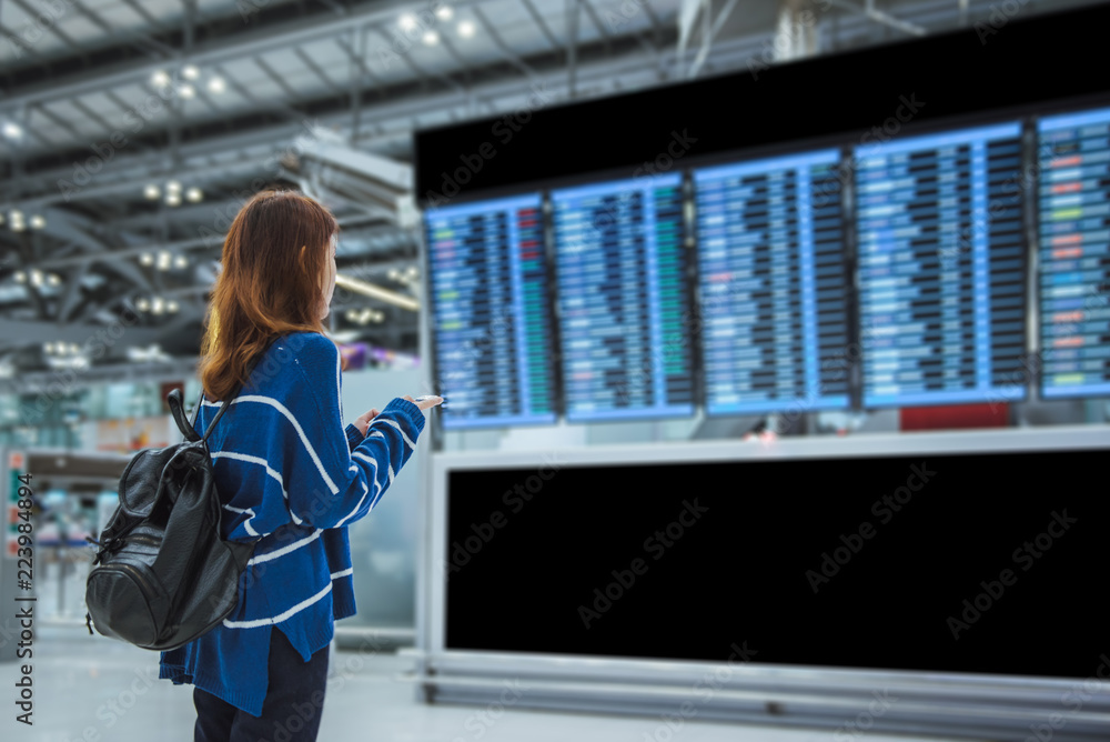 Young woman traveler in international airport looking at the flight ...