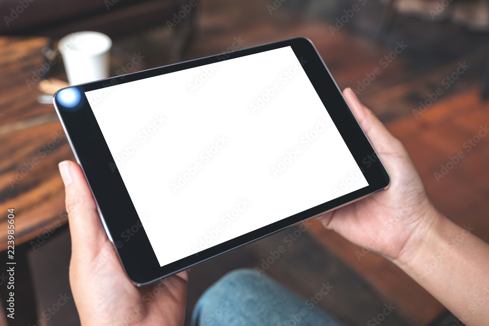 Mockup image of hands holding black tablet pc with blank white desktop screen