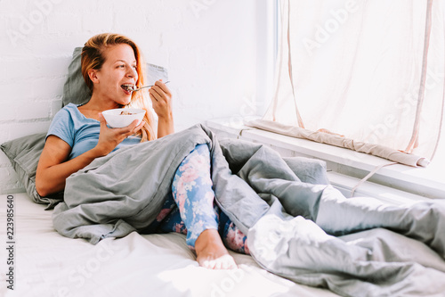Young woman eating breakfast in bed