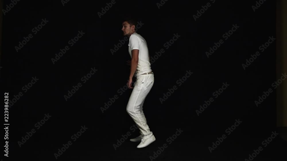 Energetic young, slim, good-looking charismatic man with big blue eyes and modern haircut dressed in white t-shirt and pants, starts running towards camera on black background. Energetic young, slim, good-looking charismatic man with big blue eyes and modern haircut dressed in white t-shirt and pants, starts running towards camera on black background.