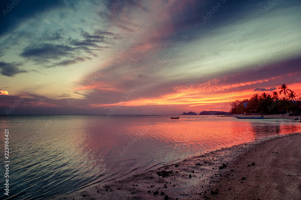 Bright colorful sunset, sandy shore of the tropical sea, palms on the shore, low tide