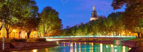  The night panoramic view of Aura river in Turku, Finland with a clock tower of cathedral and bridge on a background.                  
