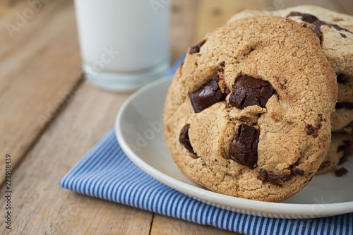 Close up picture of chocolate cookies in plate and a cup of milk