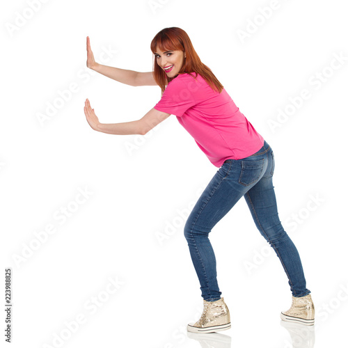 Smiling Young Woman Is Pushing Something With Two Hands