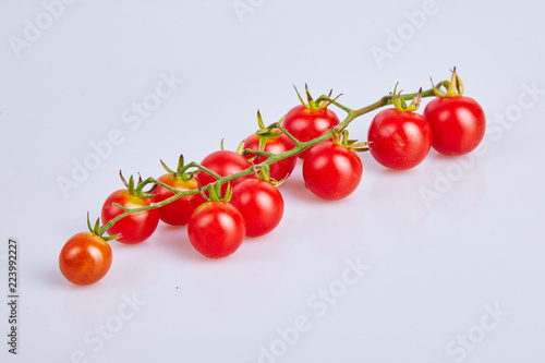 Branches of red organic fresh cherry tomatoes on a white background. Top view © Liudmila