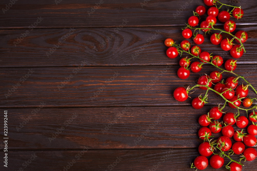Branches of red organic fresh cherry tomatoes on a wooden background. Top view Branches of red organic fresh cherry tomatoes on a wooden background. Top view