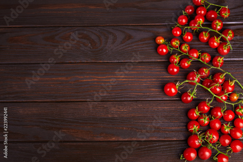 Branches of red organic fresh cherry tomatoes on a wooden background. Top view