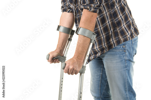 Fotografiet Close up of a man walking with crutches isolated on a white background