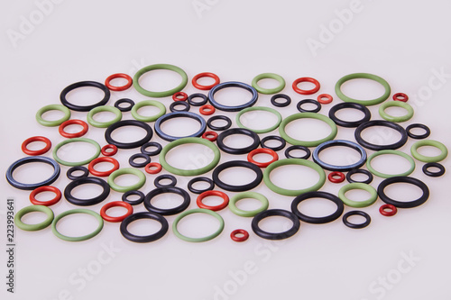 Black, red and gre hydraulic and pneumatic o-ring seals of different sizes scattered a white background. Rubber rings. Sealing gaskets for hydraulic joints. Rubber sealing rings for plumbing. Top view