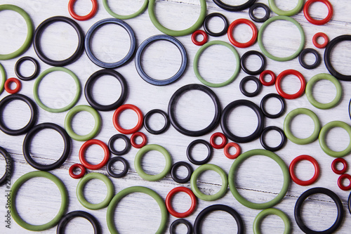 Black, red and gre hydraulic and pneumatic o ring seals of different sizes scattered a white background. Rubber rings. Sealing gaskets for hydraulic joints. Rubber sealing rings for plumbing. Top view