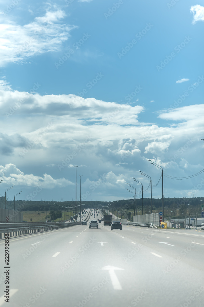 Cars on the highway. Asphalt road under the blue sky
