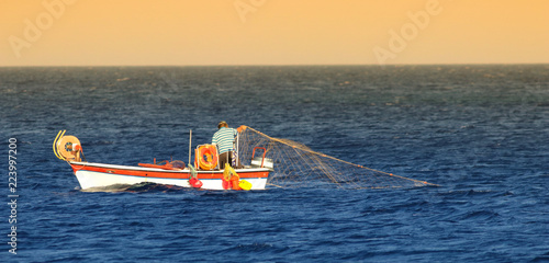 Greek fishermen fishing with net on the boat