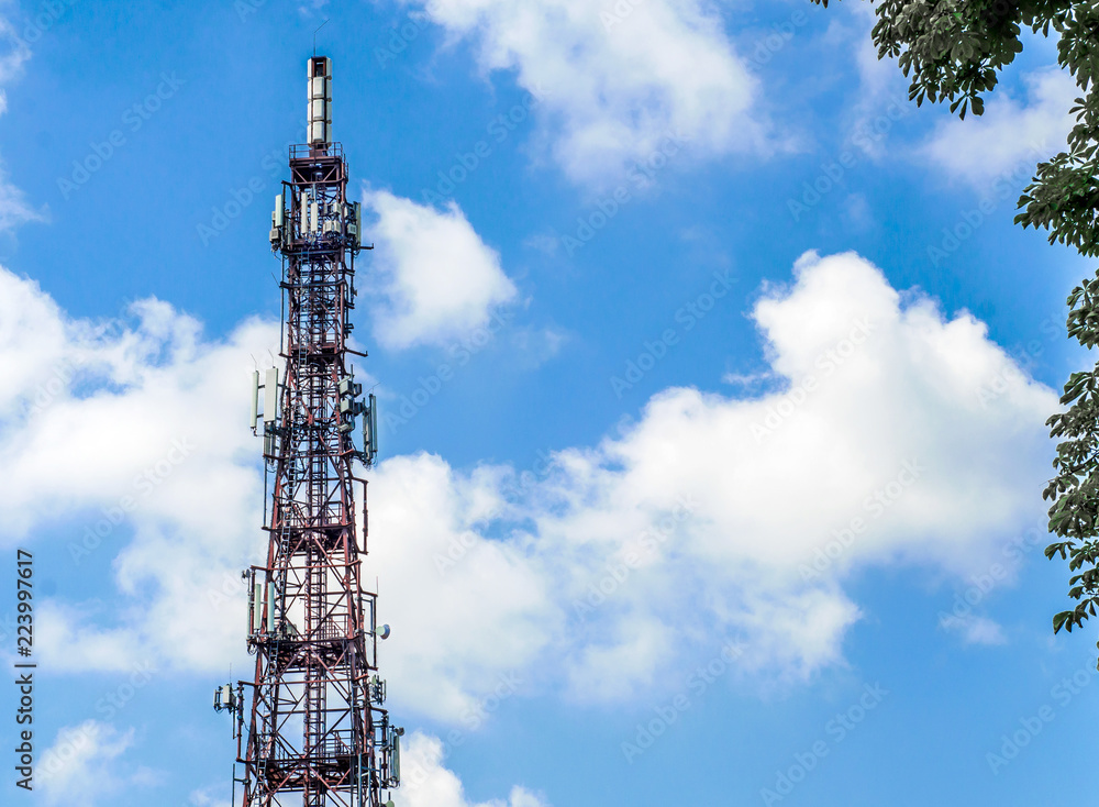 Telecommunication tower with mobile communication antennas on a background of clouds, sky
