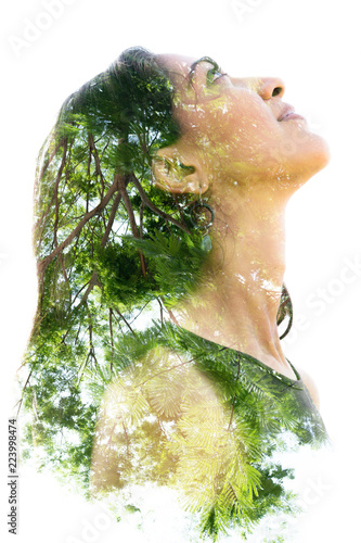 Double exposure portrait of a naturally beautiful happy woman and a tree with bright green leaves