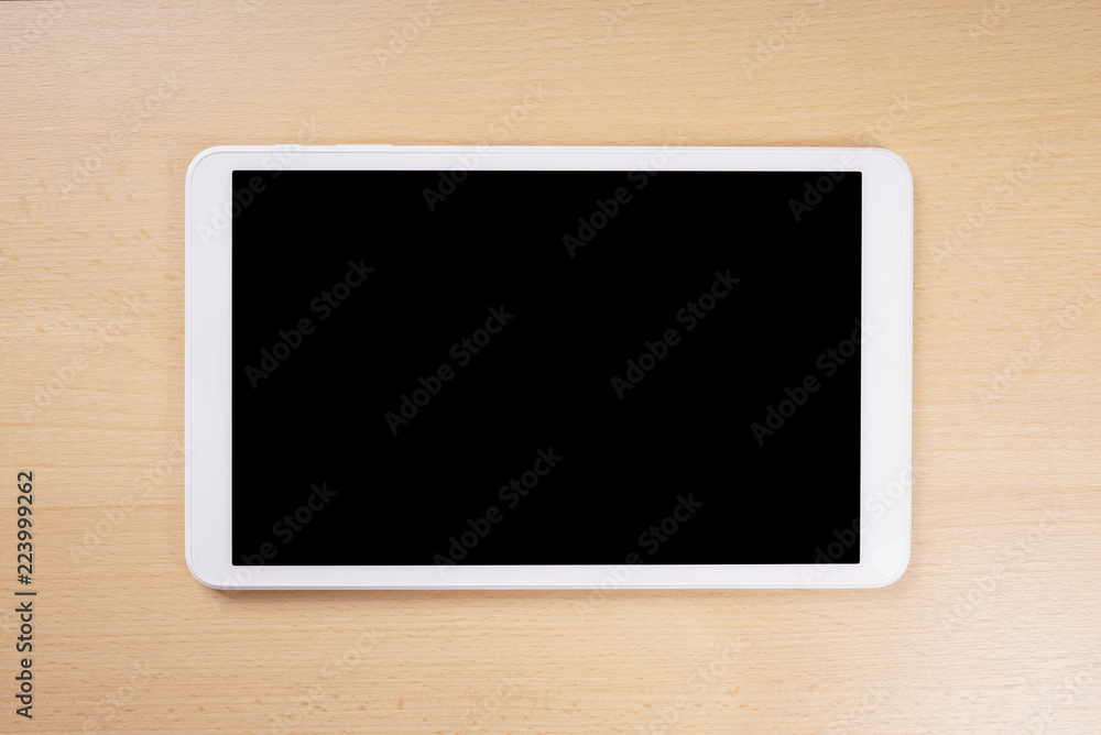 tablet computer with blank display lying on wooden desk tablet computer with blank display lying on wooden desk