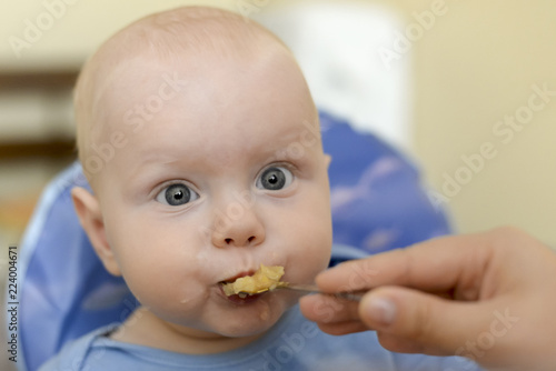 Mom feeds her son from a spoon with applesauce