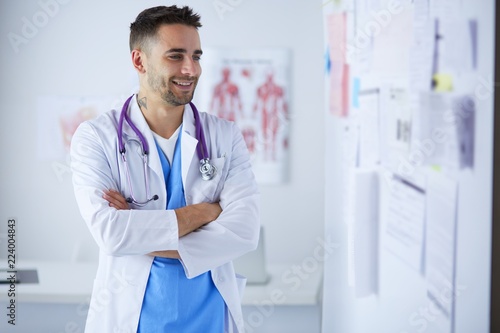 Young and confident male doctor portrait standing in medical office. photo