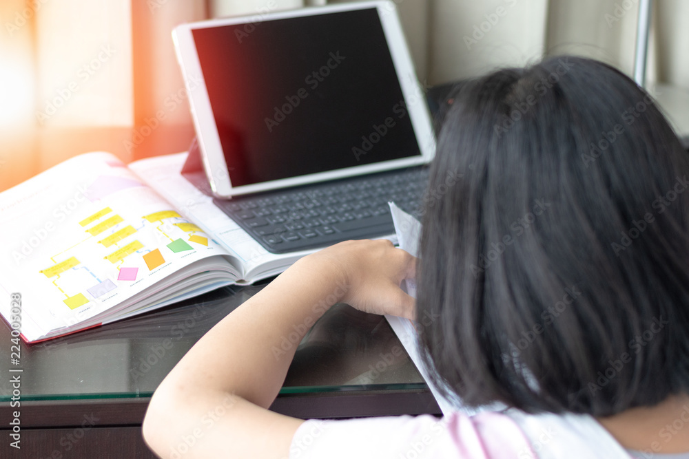 Fototapeta premium School girl student study doing homework using app in tablet computer with textbook. Education technology smart concept.