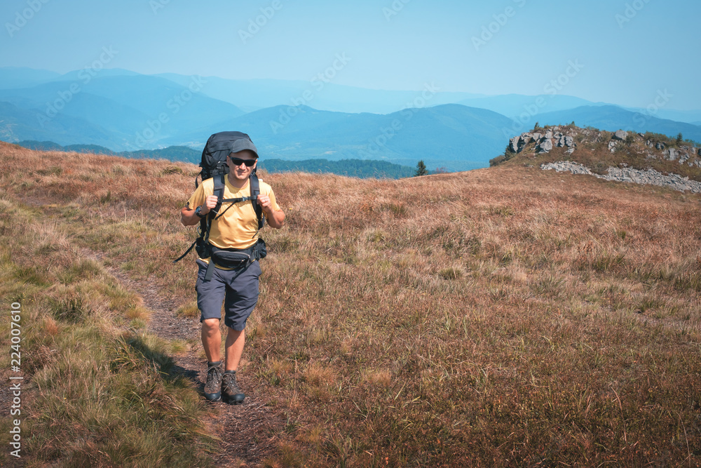 Alone tourist hiking in the mountains against the backdrop of an incredible autumn landscape. Sunny day and cloudy sky Alone tourist hiking in the mountains against the backdrop of an incredible autumn landscape. Sunny day and cloudy sky