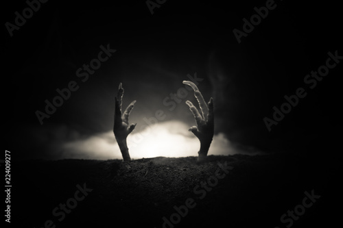 Halloween concept  zombie hand rising out from the ground or zombie hand coming out of his grave