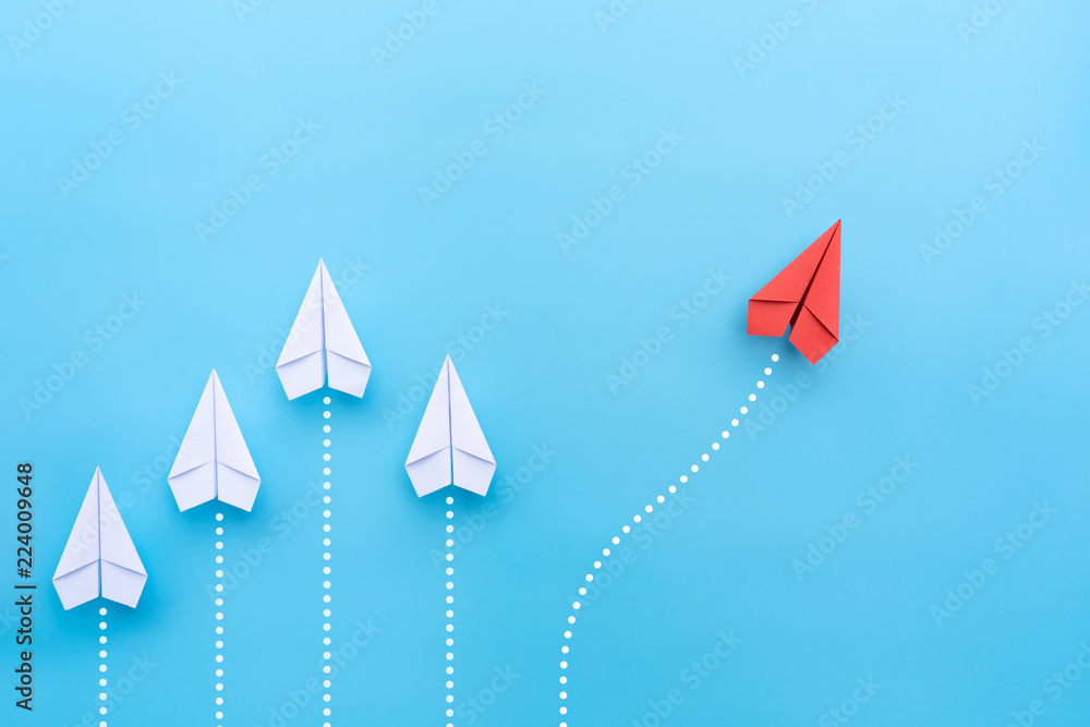 Group of white paper planes in one direction and one red paper plane pointing in different way on blue background. Business for new ideas creativity and innovative solution concepts. - obrazy, fototapety, plakaty 