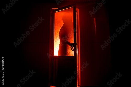 Silhouette of an unknown shadow figure on a door through a closed glass door. The silhouette of a human in front of a window at night. Scary scene halloween concept