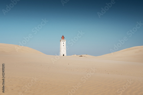 Cliff sand dunes and ocean view landscape in bright sun light and blue sky. View of the famou danish lighthouse. Rubjerg Knude Lighthouse, Lønstrup in North Jutland in Denmark, Skagerrak, North Sea