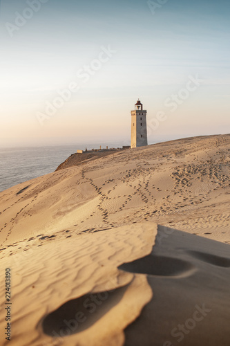 Famous danish Lighthouse and coastline sand dunes is a popular travel trip. Landscape in colorful sunset light. Rubjerg Knude Lighthouse, Lønstrup in North Jutland in Denmark, Skagerrak, North Sea