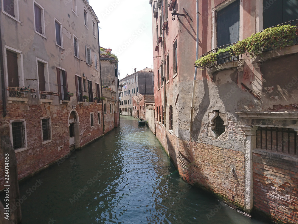 Naklejka premium Widok na historyczną architekturę i kanał między antycznymi budynkami w Wenecja, Włochy podczas radosnych wakacji w słonecznym dniu.