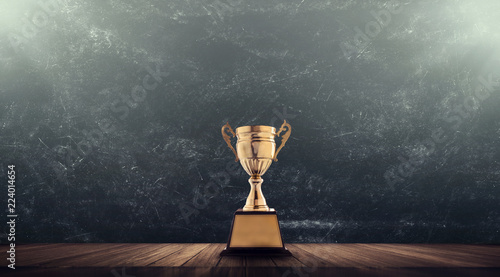 champion golden trophy placed on wooden table with blackboard background copy space ready for your design win concept.. photo