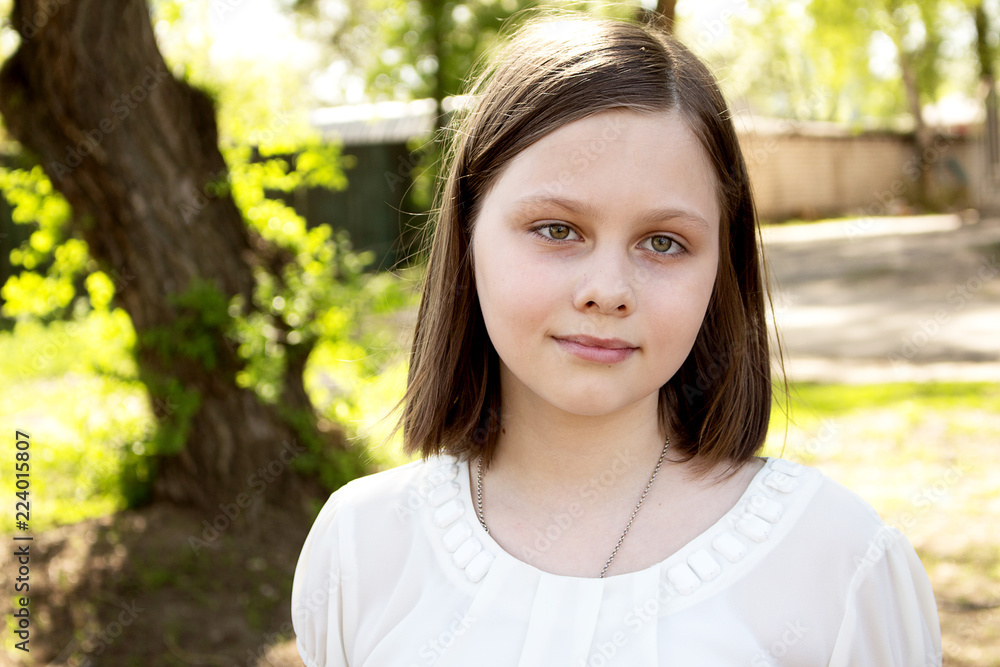 Fototapeta premium Portrait of a teenage girl, in strict clothing. The girl in the park