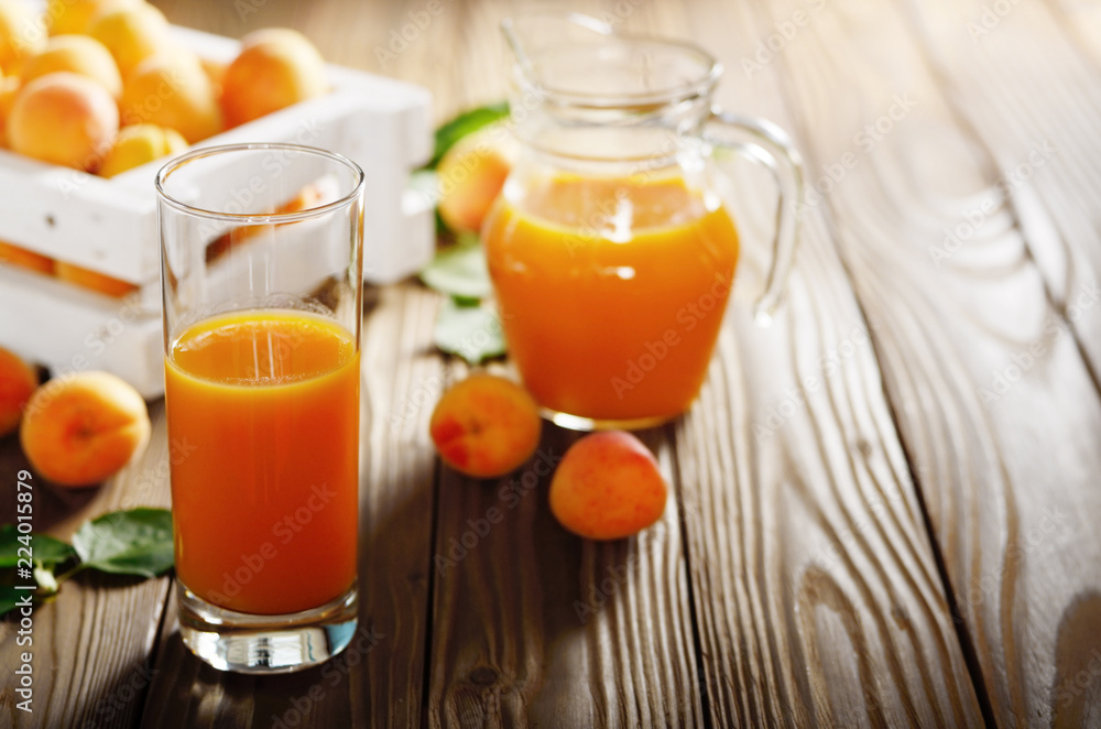 Apricot smoothie in glass on wooden table with crate and jug at background Apricot smoothie in glass on wooden table with crate and jug at background
